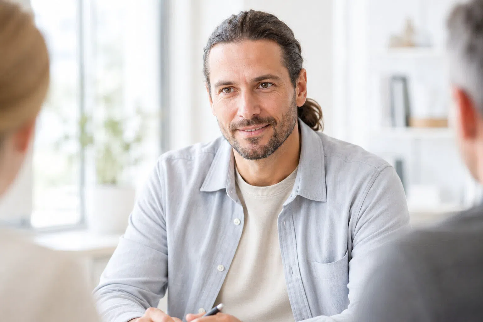 Ein Mitarbeiter im Gespräch mit zwei Kolleg*innen am Besprechungstisch